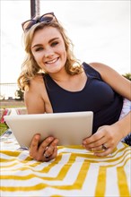 Caucasian teenage girl using tablet computer in park