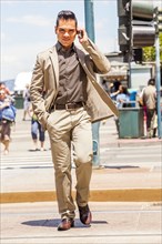 Hispanic businessman talking on cell phone in urban crosswalk