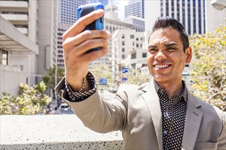 Hispanic businessman taking cell phone selfie