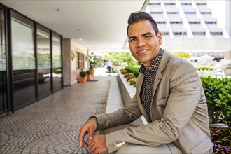Hispanic businessman leaning over outdoor bench