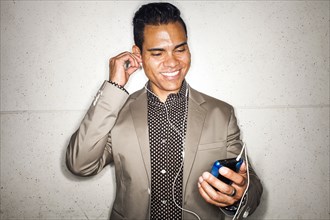 Hispanic businessman listening to earbuds with cell phone