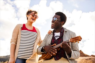Couple singing together and playing ukulele outdoors