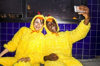 Couple taking cell phone selfies wearing chicken costumes