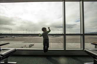 Mixed race boy looking out airport window