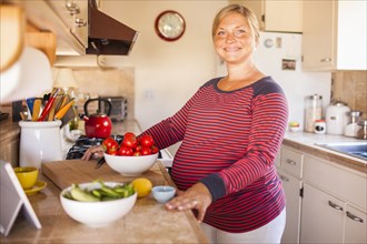 Pregnant Caucasian mother cooking in kitchen