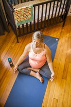 Pregnant Caucasian woman meditating in nursery