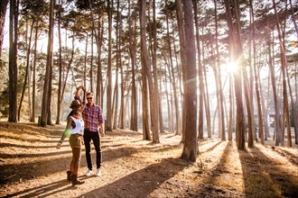 Couple holding hands under trees in sunny forest