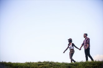 Couple walking together in grassy field
