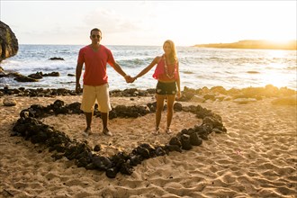 Couple holding hands in heart shape on beach