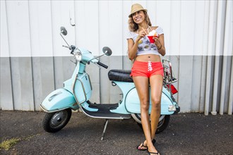 Woman eating shave ice near scooter