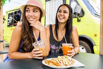 Pacific Islander women eating and drinking near food cart