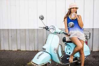 Pacific Islander woman drinking iced coffee on scooter