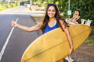 Pacific Islander surfer hitch hiking on rural road