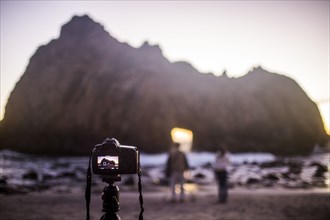 Camera on self-timer taking photograph of couple on beach