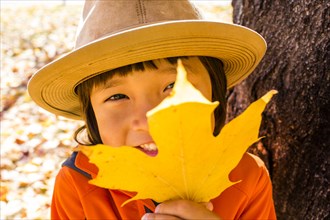 Close up of smiling mixed race boy holding autumn leaf