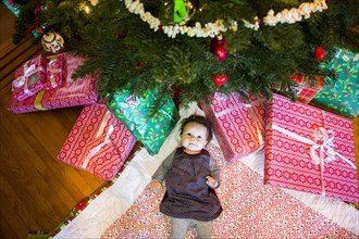 High angle view of Caucasian baby girl laying under Christmas tree