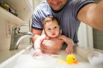 Close up of Caucasian father bathing baby girl in sink