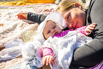 Close up of Caucasian mother and baby girl laying on blanket