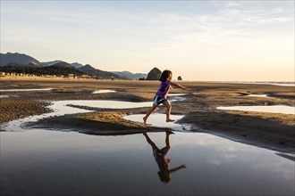 Caucasian girl running in tide pools on beach