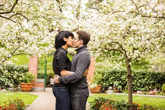 Couple kissing under flowering trees in park