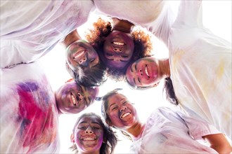 Low angle view of smiling friends covered in pigment powder