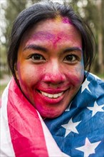 Smiling Asian woman covered in pigment powder wearing American flag