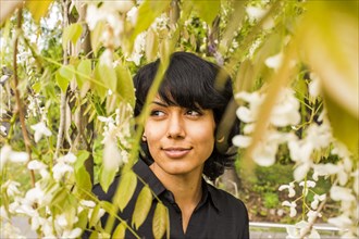 Hispanic woman smiling in foliage