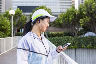 Asian runner using cell phone in city