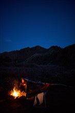 Caucasian man sitting near campfire in remote landscape