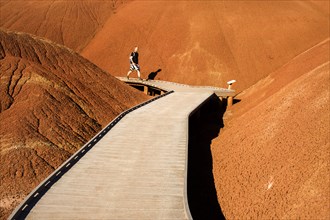 Caucasian hiker on wooden walkway in desert hills