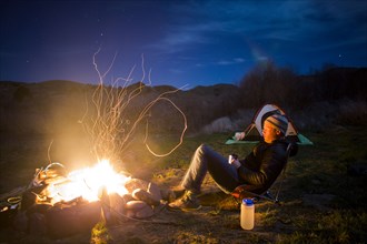 Caucasian man relaxing near campfire in remote field