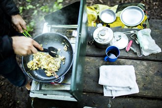 Caucasian man cooking eggs at campsite