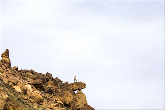 Caucasian hiker standing on sheer cliff boulder