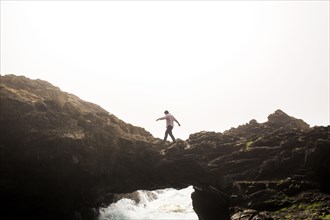 Caucasian man walking on bridge over ocean waves