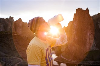 Caucasian man drinking water bottle in desert landscape