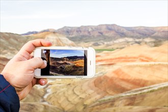 Caucasian man taking cell phone photograph of desert landscape