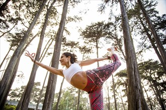 Hispanic woman practicing yoga in forest