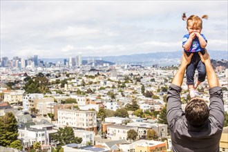 Caucasian father lifting daughter over San Francisco cityscape