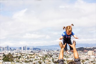 Caucasian father tossing daughter over San Francisco cityscape