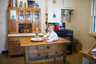 Caucasian baby girl sitting on kitchen table