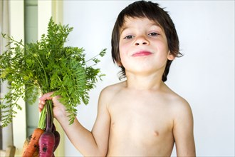 Mixed race boy holding fresh picked carrots