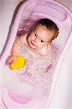 Caucasian baby girl sitting in bathtub