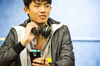 Asian man with headphone using cell phone