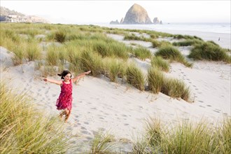 Caucasian girl running with arms outstretched on beach