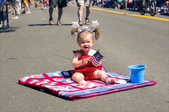 Caucasian girl sitting on quit at 4th of July parade