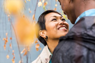 Close up of smiling couple standing in autumn leaves