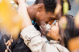 Close up of smiling couple hugging in autumn leaves