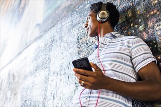 Man listening to cell phone by mural