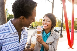 Smiling couple eating ice cream in park