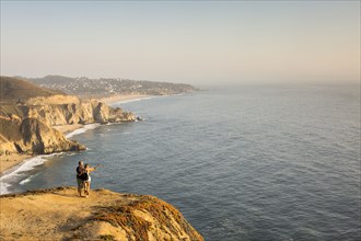 Caucasian couple on cliff admiring seascape
